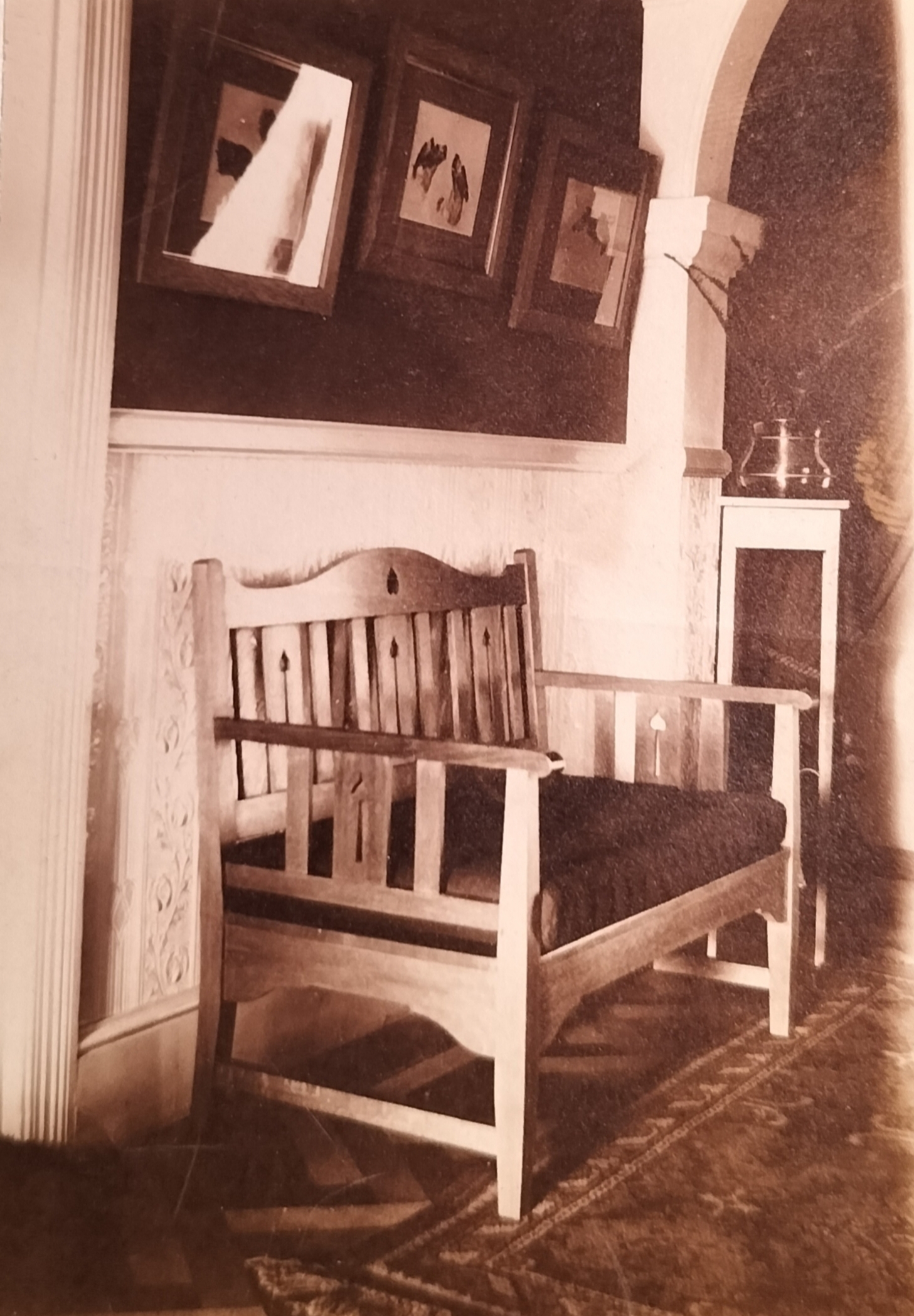 A wooden bench with three framed prints featuring dogs. This bench in all probability stands across from the hallstand seen in an image above. Note the Persian carpet on the parquet flooring.