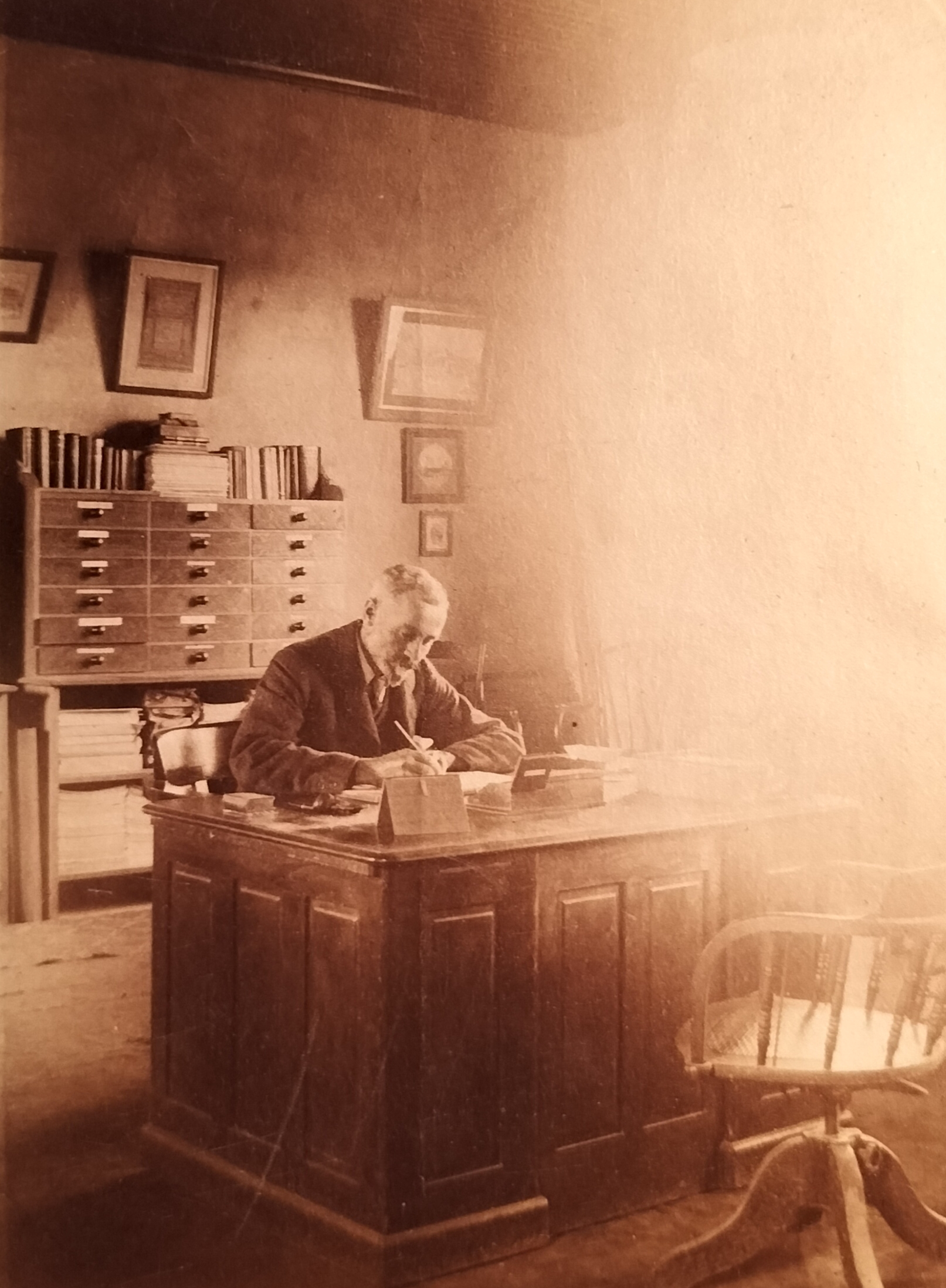 The male occupant of the house in his study with a unique filing system behind him. The light flooding into the study, blurring a third of the photograph, provides for an unintended special effect.