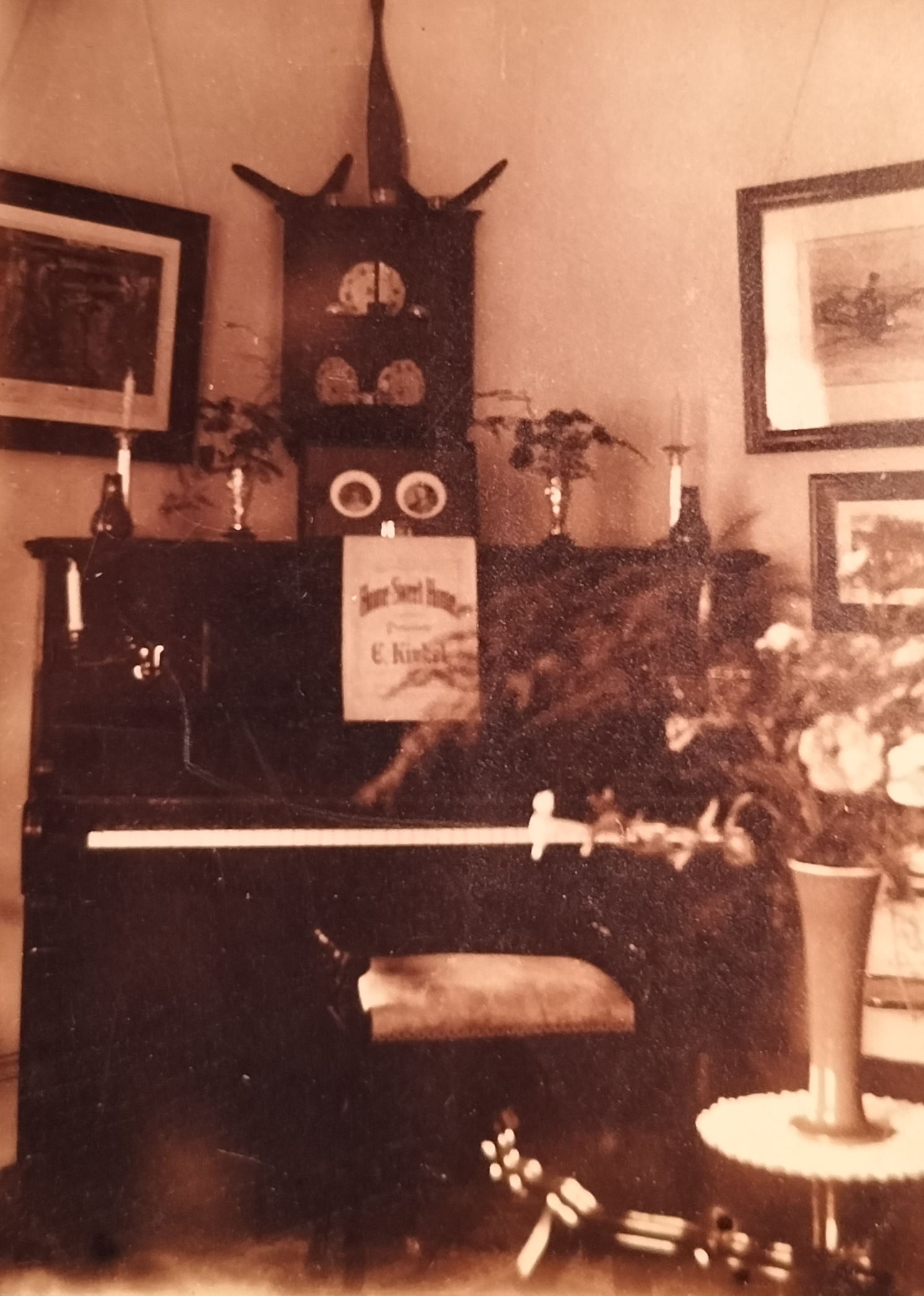 “Home Sweet Home” music sheet on the piano. Note the candles on either side of the piano. On top of the piano seems to be photographs of the couple who occupied the house.