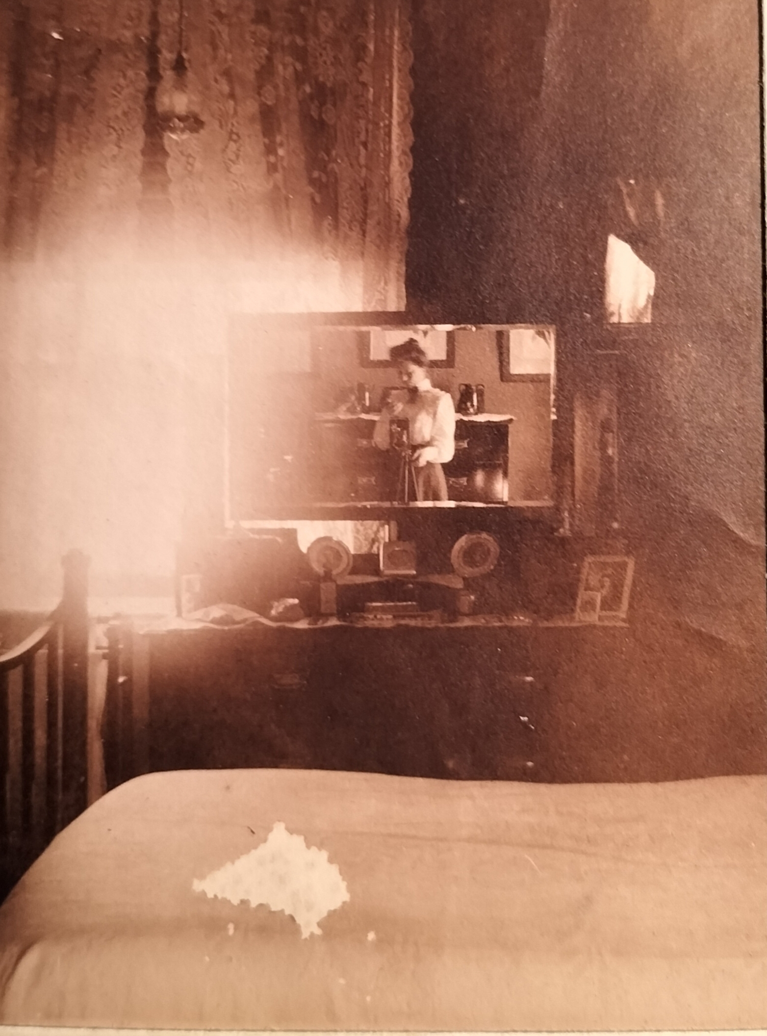 In the main bedroom. Here the female photographer inadvertently captured herself in action. The sideboard in the room also holds a number of family photographs. Although the white spot on the bed seems like a damaged photograph, it is actually a handcrafted piece of material.